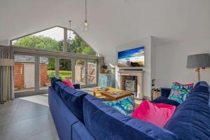 un sofá azul en una sala de estar con una gran ventana en 'The School House' - Luxury Home with Large Garden en Long Melford