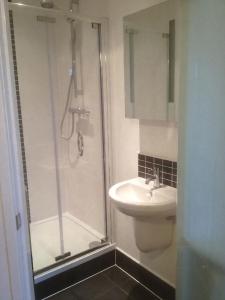 uma casa de banho com um chuveiro e um lavatório. em Park House B&B em Leeds