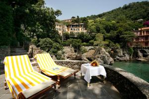 two lawn chairs and a table on a bridge over water at Hotel Piccolo Portofino in Portofino