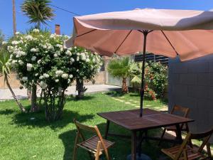 a wooden table with an umbrella and chairs in a yard at GK Home I part of Gk Fitness Club in Faliraki