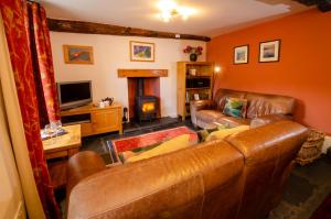 a living room with a leather couch and a fireplace at Peggy Hill Cottage in Ambleside