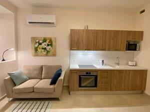 a living room with a couch and a kitchen at Mosta Garden Studio in Mosta