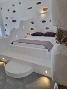 a white bedroom with a white bed with pillows at Nikola's place II in Astypalaia Town