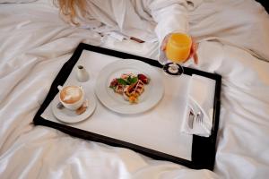 a person holding a tray of food on a bed at Crowne Plaza Bratislava, an IHG Hotel in Bratislava