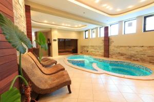 a large pool in a room with a chair and a couch at Hotel Winpalace in Arbanasi