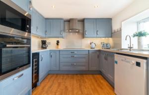 a kitchen with blue cabinets and a wooden floor at Rowan Cottage at Kames in Kames