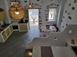 a white kitchen with a table and aendant light at Nikola's place II in Astypalaia