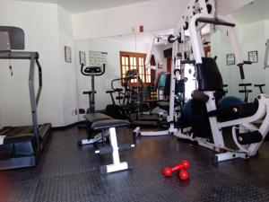 une salle de sport avec plusieurs machines à bande de roulement et poids rouges dans l'établissement Pousada Canto da Paz, à Petrópolis