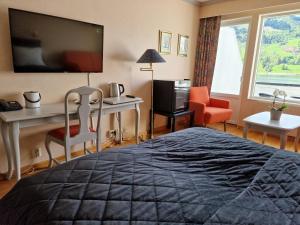 una camera d'albergo con letto, scrivania e TV di Olden Fjordhotel a Olden