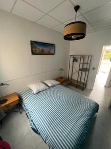 a bedroom with a bed with a blue and white striped blanket at Appartement en face de la plage avec barbecue in Plage dʼArgelès