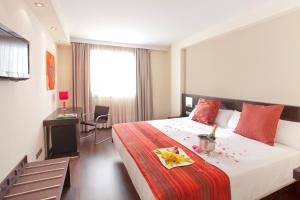 a hotel room with a bed and a desk and a room at Sercotel Aura Algeciras in Algeciras