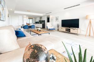 een woonkamer met een bank en een tv bij Alcazaba Lagoon Apartment with Private Beach, Pools, Gym, Sauna, Hot Tub & Fully Equipped Kitchen in Casares