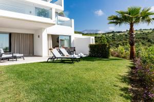 een wit huis met een gazon en een palmboom bij Alcazaba Lagoon Apartment with Private Beach, Pools, Gym, Sauna, Hot Tub & Fully Equipped Kitchen in Casares +65 foto's