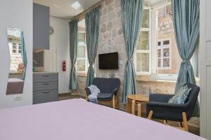 een slaapkamer met een bed en 2 stoelen en een televisie bij Studio Nikol in Dubrovnik