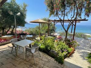 a patio with a table and chairs and the ocean at Horizon Beach Hotel in Plakias