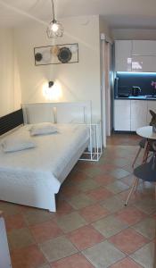 a bedroom with a white bed and a kitchen at Romir Pokoje Bardzo Gościnne in Sztutowo