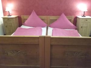 a large wooden bed with pink pillows on it at Haus Pollak in Waldkirchen