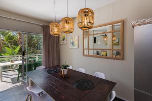 a dining room with a wooden table and chandeliers at Casablanca 6 in Ballito