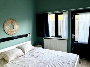 a bedroom with a white bed and a green wall at Holiday home Beachy Days near ocean & lake in Noordwijkerhout +26 photos