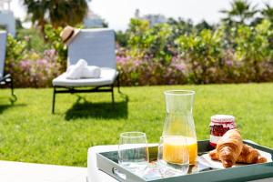 een dienblad met brood en een fles sinaasappelsap en glazen bij Alcazaba Lagoon Apartment with Private Beach, Pools, Gym, Sauna, Hot Tub & Fully Equipped Kitchen in Casares