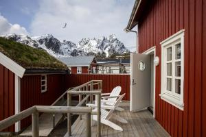 a red house with a deck with a table and chairs at Solsiden Brygge Rorbuer in Ballstad