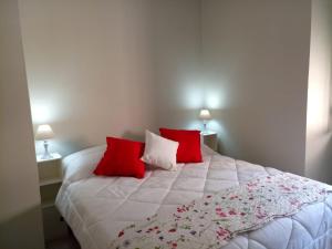 a bedroom with a white bed with red pillows at La Casa di Tagliacozzo delizioso appartamento centrale con 2 camere e camino in Tagliacozzo