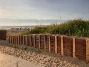 einen Holzzaun an einem Sandstrand in der Nähe des Ozeans in der Unterkunft FeWo Tietjen-Lohse, mit Meerblick, Strandhochhaus F9 in Cuxhaven