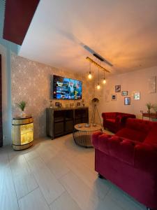 ein Wohnzimmer mit einem roten Sofa und einem TV in der Unterkunft Ferienhaus Nicole II, Barrierefrei, mit HIRO Lift in Quedlinburg