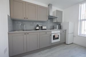 a kitchen with white cabinets and a sink and a refrigerator at Platform Stadium apartment with parking in Hull