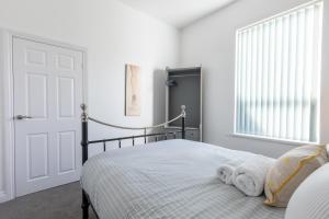 a bedroom with a bed with white walls and a window at Platform Stadium apartment with parking in Hull