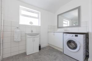 a white bathroom with a sink and a washing machine at Platform Stadium apartment with parking in Hull