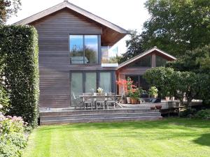 a house with a deck with a table and chairs at Pound Orchard Bed and Breakfast in Petersfield