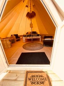 une tente avec un tapis de bienvenue au milieu d'une pièce dans l'établissement Bell Tent, à Heerewaarden