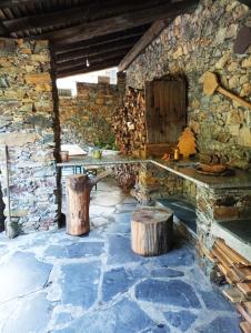 uma sala de pedra com uma mesa e dois troncos em Casa do Rio em Coimbra