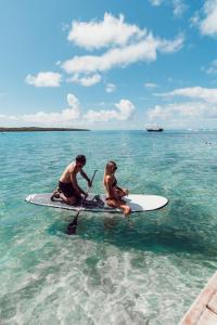 a man and a woman on a surfboard in the water at Preskil Island Resort in Mahébourg