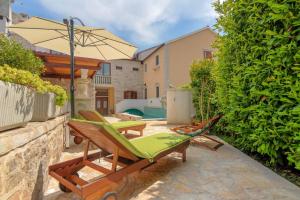 a patio with a couple of chairs and an umbrella at 4 bedrooms seafront Villa LAURUS with heated pool for up to 8 people in Sumartin