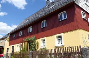 uma casa vermelha e amarela com uma cerca de madeira em FeWo Dorn OG Haus Sandsteinliebe em Sebnitz