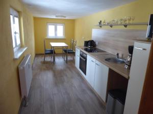 uma cozinha com um lavatório e uma mesa com cadeiras em FeWo Dorn OG Haus Sandsteinliebe em Sebnitz