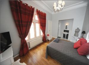 - une chambre avec un lit et une fenêtre avec des rideaux rouges dans l'établissement La Demeure de Laclais, au Mans