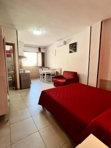 un soggiorno con letto rosso e tavolo di Monolocale Rosso - A casa di Ludovica e Martina a Gallipoli