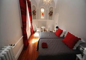 a bedroom with a bed with red pillows and a table at La Demeure de Laclais in Le Mans