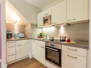 a kitchen with white cabinets and stainless steel appliances at Feriendorf Rugana - Komfortplus Appartement mit 1 Schlafzimmer und Terrasse B19 in Dranske