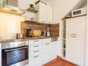 une cuisine avec des armoires blanches et une cuisinière dans l'établissement Feriendorf Rugana - Komfortplus Appartement mit 1 Schlafzimmer und Terrasse B43, à Dranske
