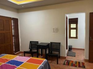 a bedroom with a bed and two chairs and a table at Maleyam Homestay in Kozhikode