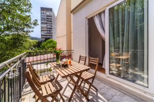 a balcony with a wooden table and chairs on it at Stay in Meta Mate in Split