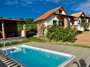 a house with a swimming pool in front of a house at Chalés Sossego da Serra in Serra de São Bento