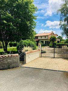 a gate in front of a house with a yard at Le refuge des canards in Saint-Aubin-le-Cloud