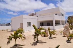 a white house with palm trees in front of it at Kasa n'areia, Praia Estoril in Sal Rei