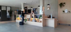 布拉尼亚克Appart Hotel Odalys City Toulouse Blagnac Aéroport的站在商店柜台后面的男人和女人 更多33张照片