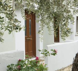 a white building with a brown door and some flowers at Olia Garden in Pachis